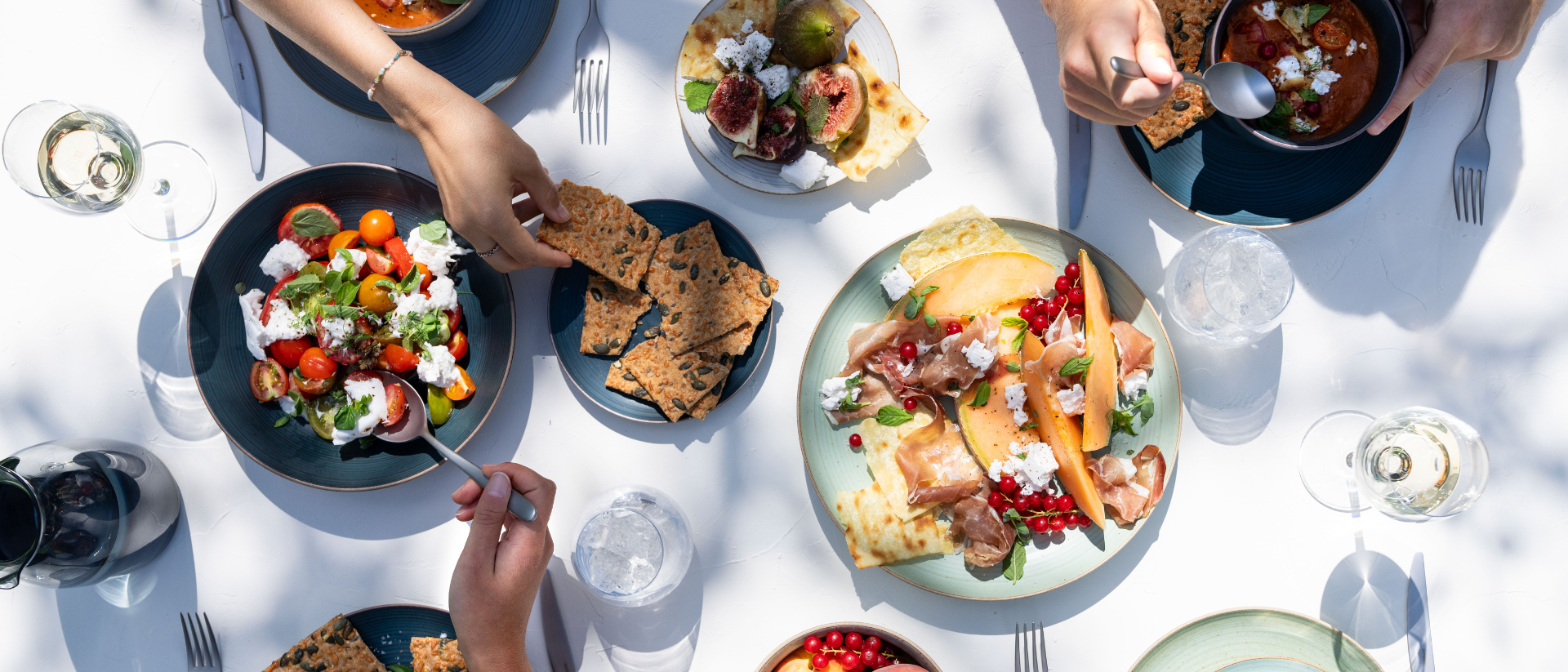 Grillparty-Tisch mit Melone, Salat, Antipasti und Thomas Geschirr im Sonnenschein