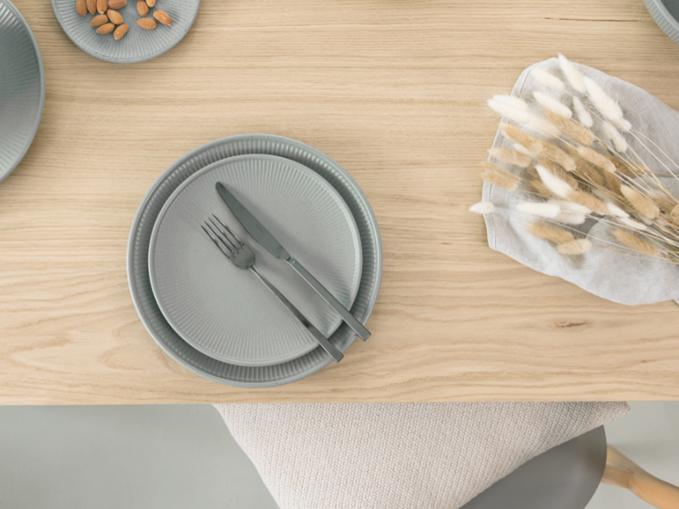 Japandi-style tableware by Thomas, featuring a grey plate and cutlery on a light wooden table with natural decorations.