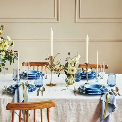 Festively laid table with blue porcelain, candles and flower arrangements
