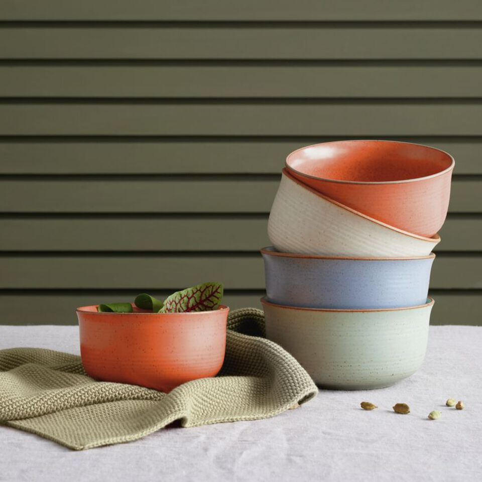 Gestapelte Thomas Schalen in warmen Farben auf einem Tisch mit Stoffunterlage
