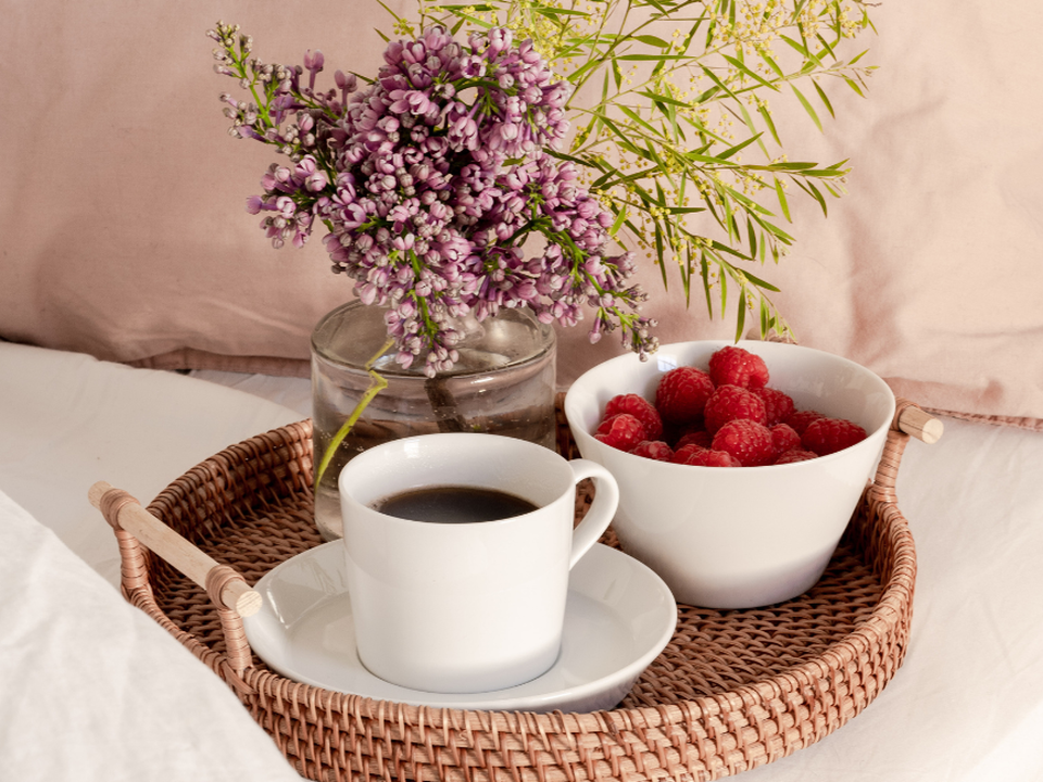 White tableware in the Japandi style by Thomas, featuring a coffee cup and a bowl of raspberries on a tray decorated with flowers.