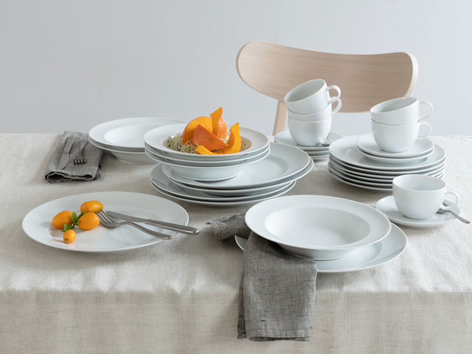 Sunny Day White plates and cups on a beige linen tablecloth, with sliced pumkins as color accents