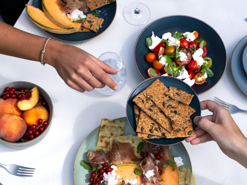 Tisch mit Melone, Salat, Antipasti und Thomas-Geschirr in der Sonne