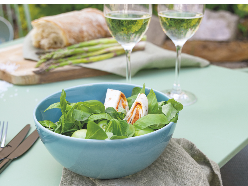 Summer garden table with salad bowl, asparagus and white wine for barbecue season