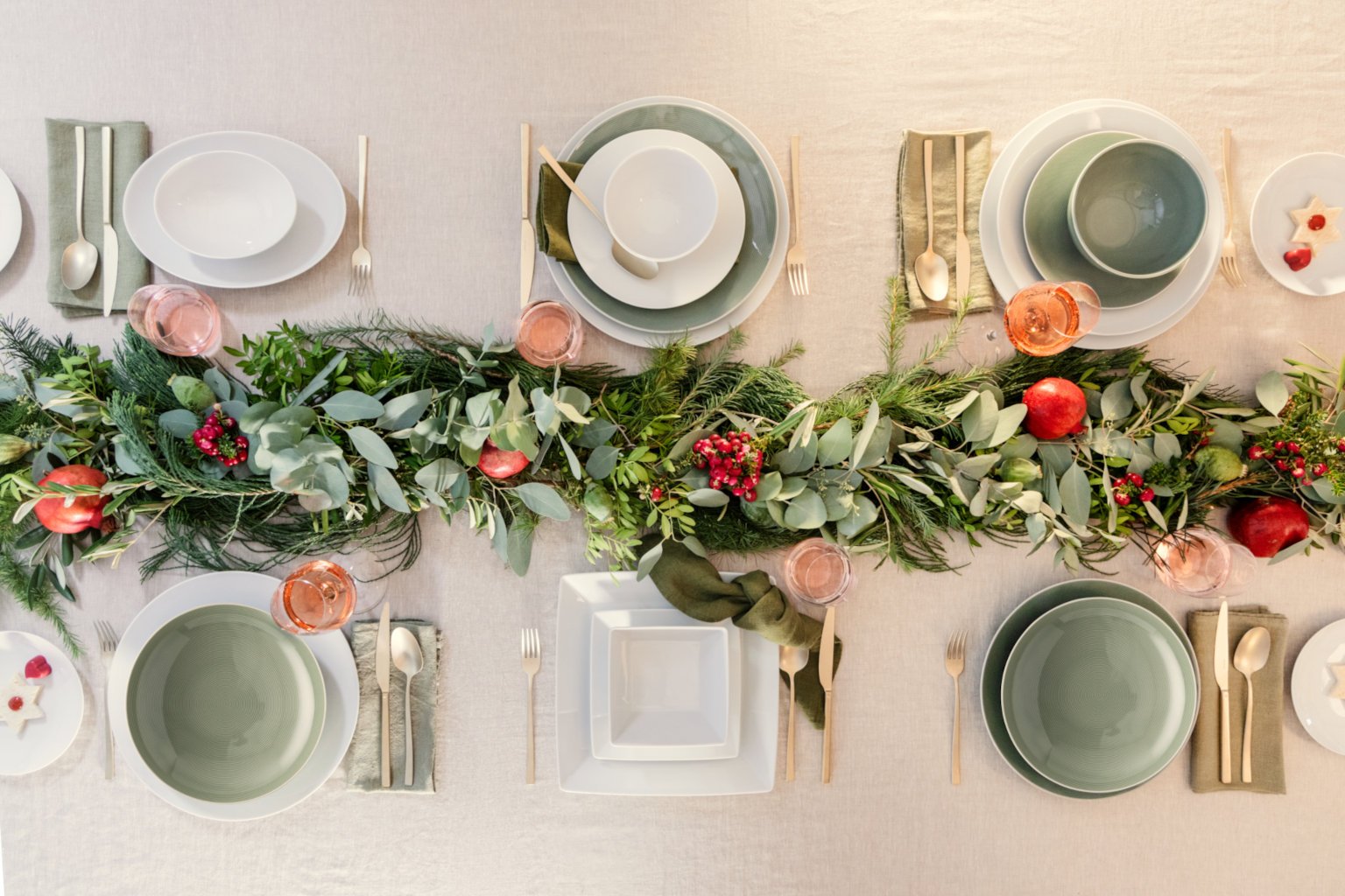 Weihnachtlich geschmückter Tisch mit Zweigen und Granatäpfeln als Deko und Thomas Loft Weiß und Moss Green Geschirr von oben fotografiert