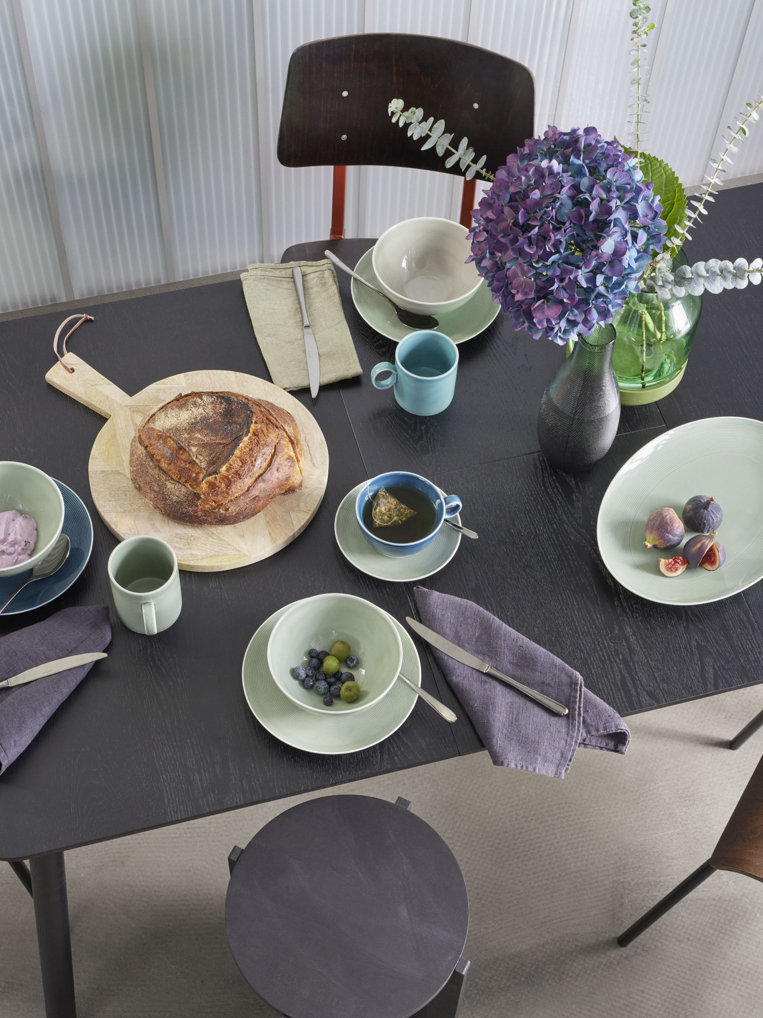 Thomas Loft Moss green Geschirr gedeckt auf dunklem Tisch mit Brot und Bilumen dekoriert