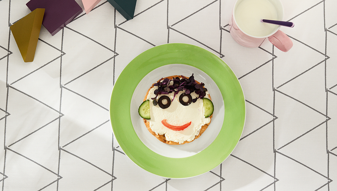 Sunny Day Apple Green Frühstücksteller mit belegtem Brot in Gesichtsform garniert