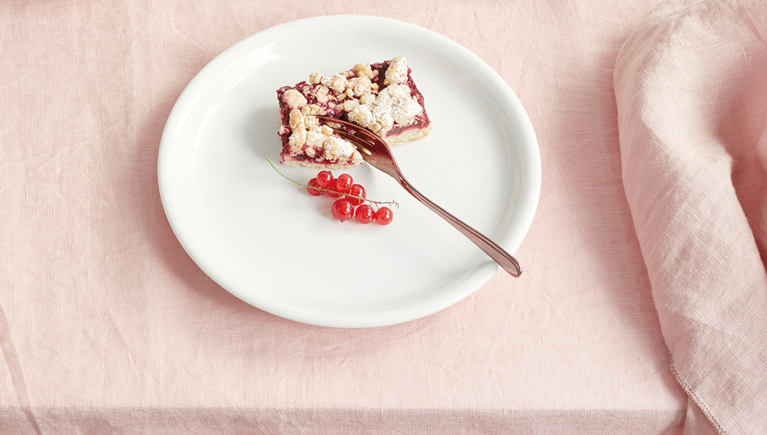 Ein Frühstücks- und Kuchenteller von Thomas Trend Weiß auf deiner rosa Tischdecke mit Streuselkuchen und Preiselbeeren